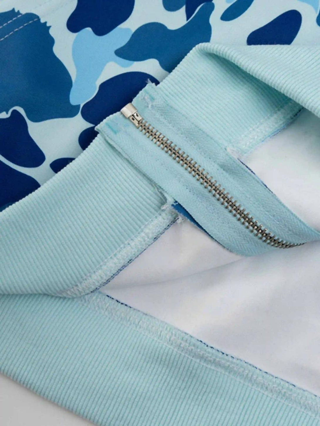 Focusing on the intricate zipper and fabric detail of TALISHKO's camouflage hoodie.