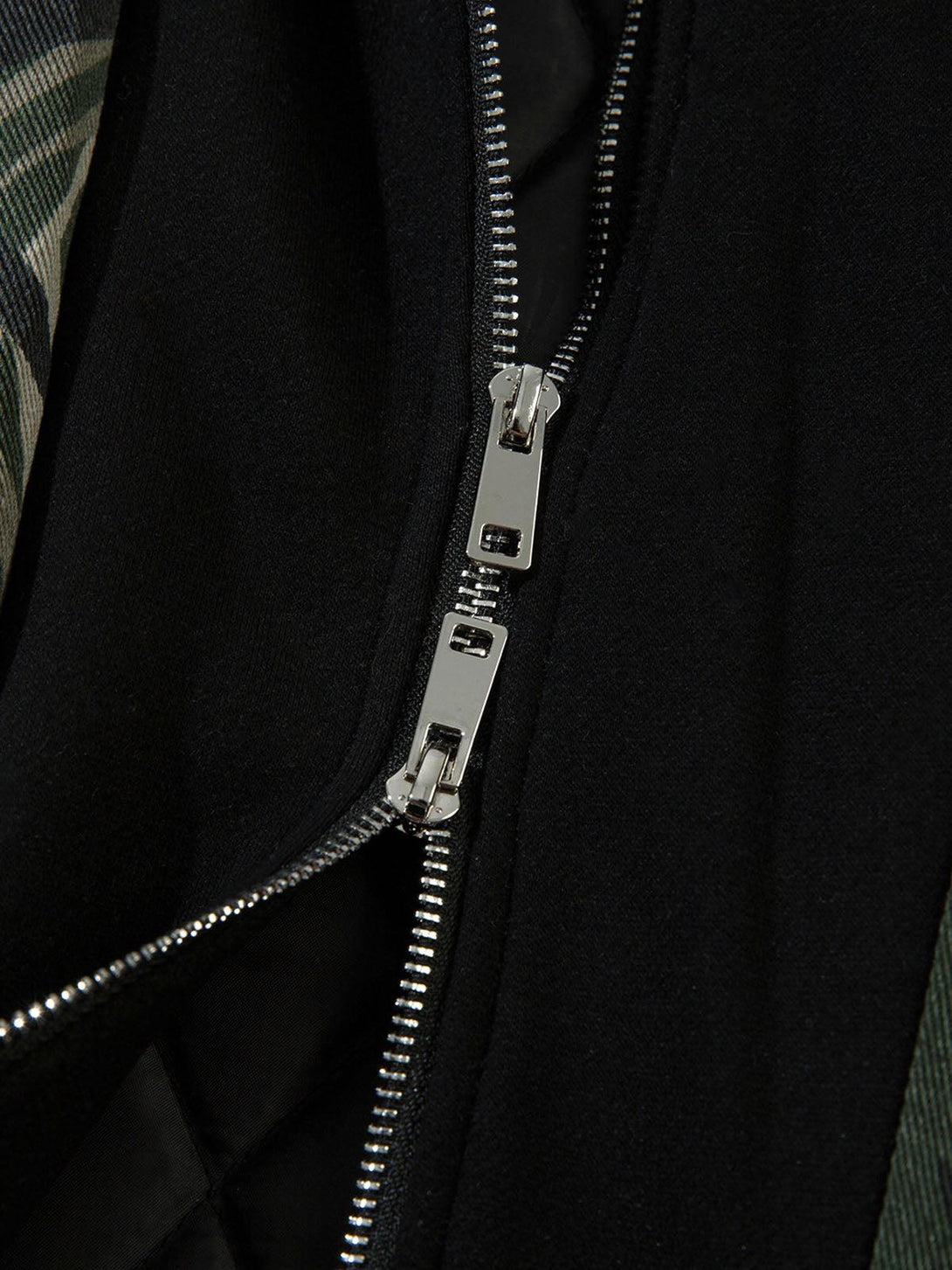 Focusing on TALISHKO's bomber jacket zipper detail, highlighting its sleek, layered design.