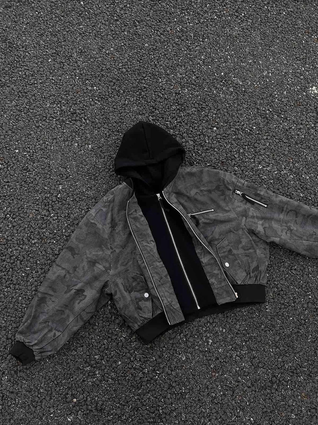 TALISHKO camouflage jacket with hood, laid on gravel, showcasing its faux two-piece style.