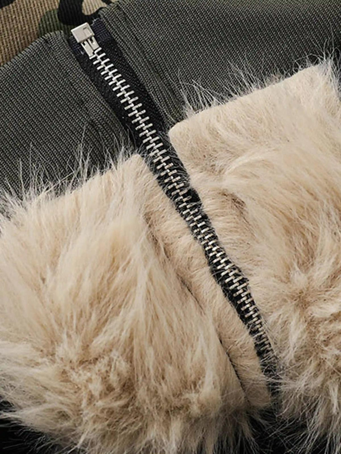 A tight crop highlighting the fur-lined zipper detail of the TALISHKO camouflage hoodie.