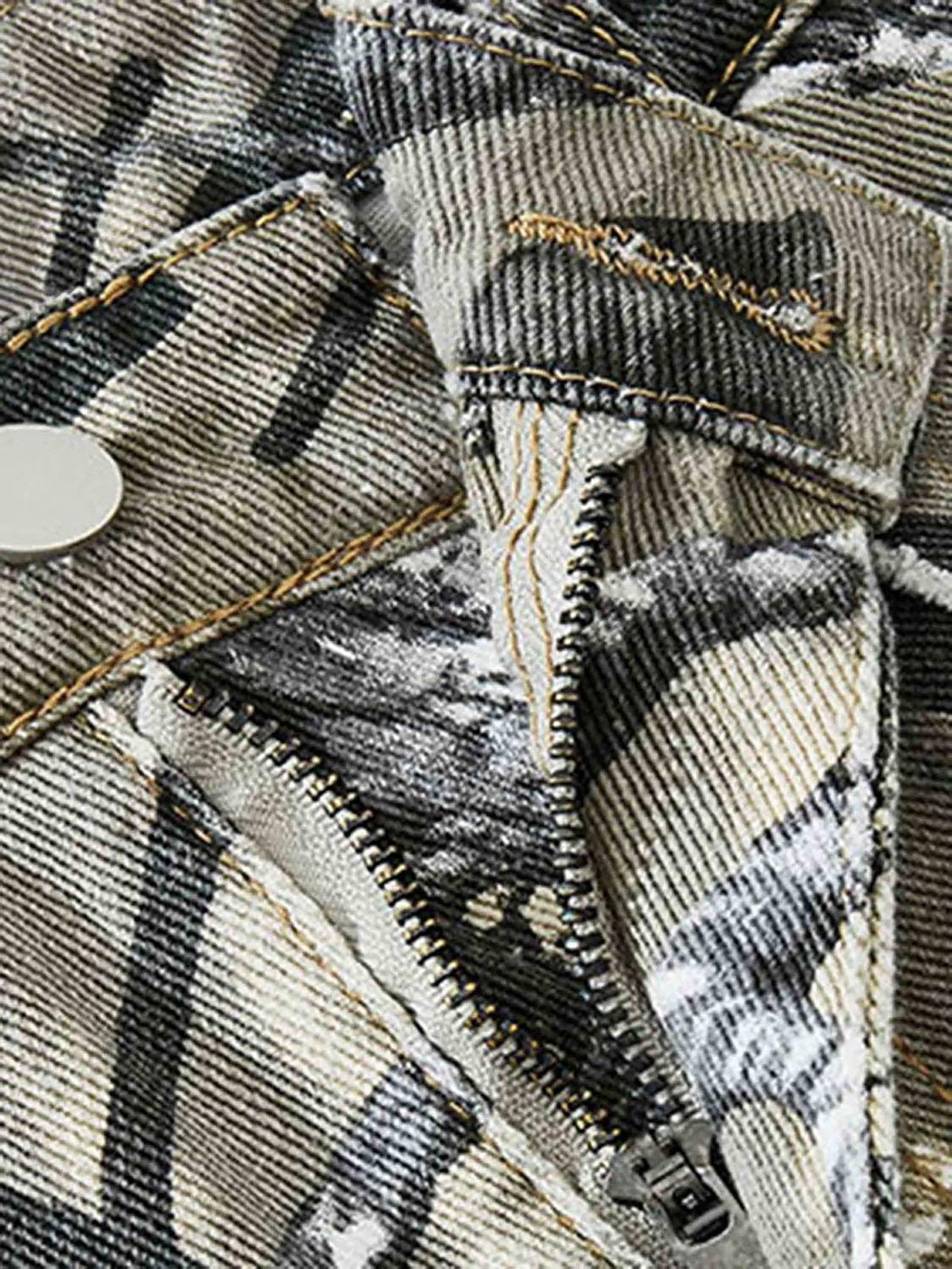 Detailed fabric and stitching of TALISHKO camouflage leaf pants with unique zipper design.