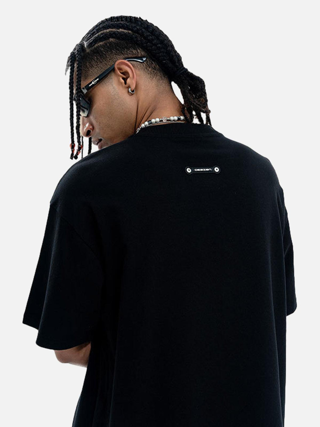Model wearing a TALISHKO black T-shirt, showcasing stylish accessories and braided hair.