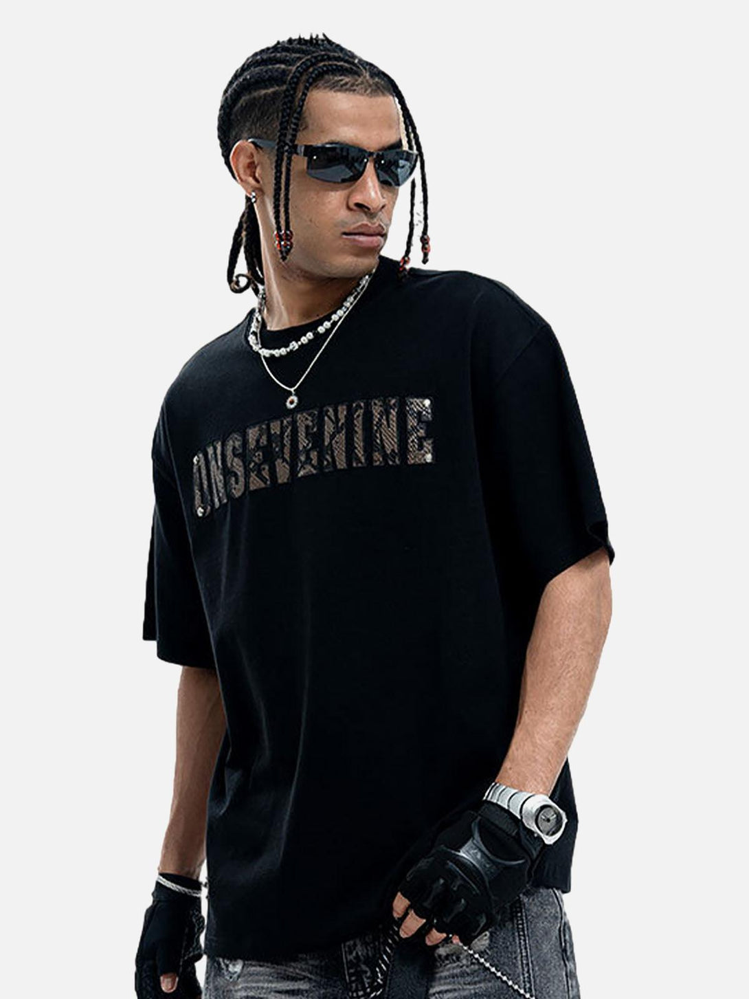 Model wearing a TALISHKO black short sleeve T-shirt with camouflage lettering and stylish accessories.