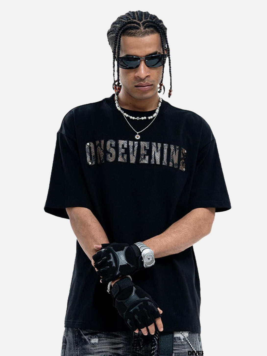 Model in TALISHKO black T-shirt with camouflage lettering, accessorized with gloves and sunglasses.