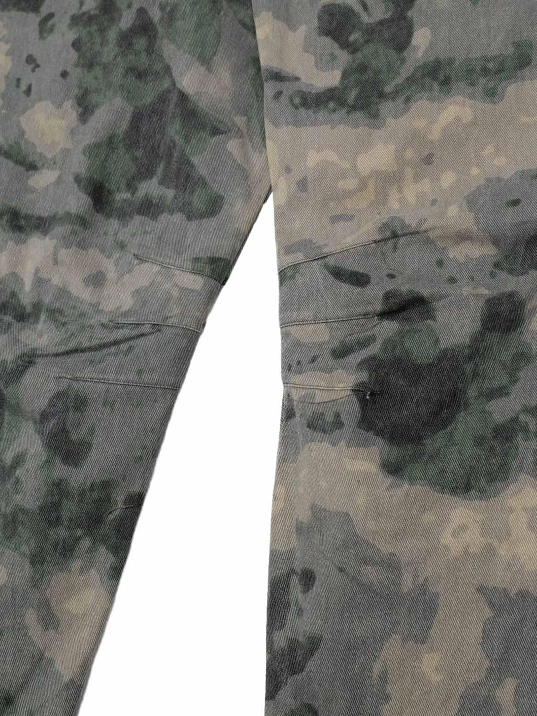 Zoomed-in texture of TALISHKO cargo pants, highlighting the camouflage pattern and stitching.