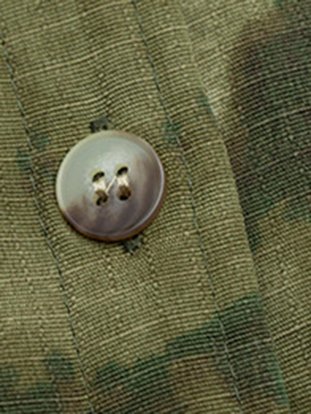 Intricate look at the TALISHKO jacket's button and camouflage fabric texture.