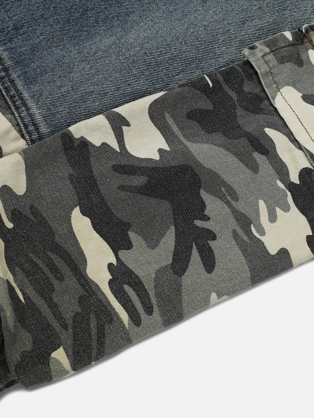 A detailed look at TALISHKO camouflage patchwork jeans, showcasing denim and camo fabric contrast.