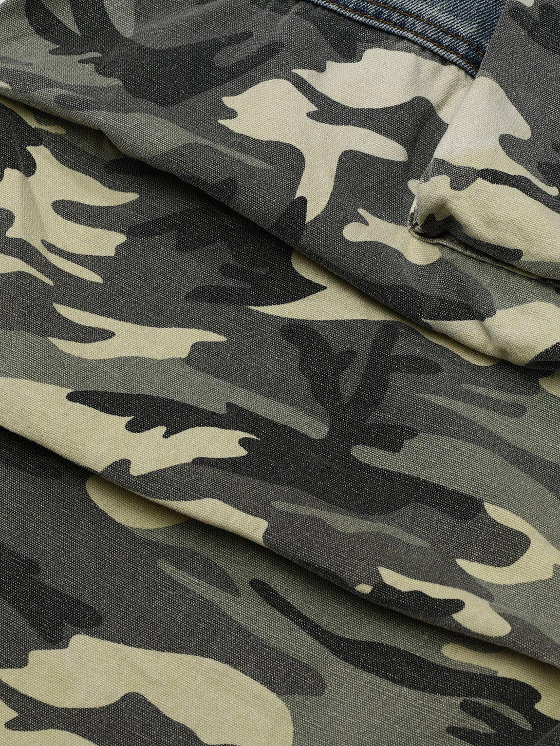 Zoomed-in texture of TALISHKO camouflage patchwork jeans, highlighting intricate fabric design.