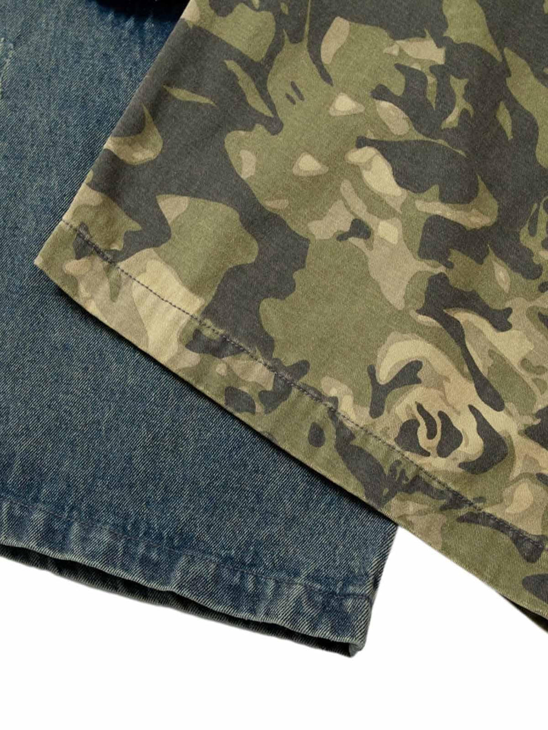 Detailed fabric and stitching of TALISHKO's camouflage patchwork on denim jeans.