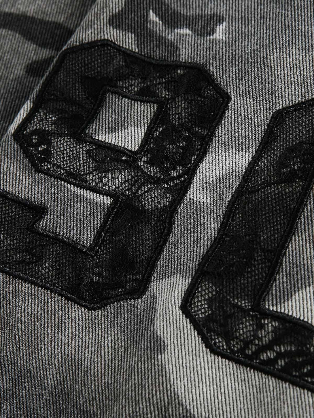 Zoomed-in view of TALISHKO's denim shirt, showcasing lace detailing and camouflage pattern.