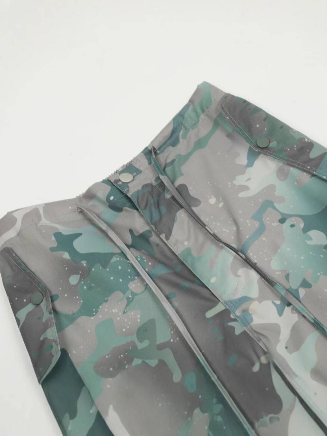 Camouflage tie-dye pattern and button detail on TALISHKO cargo pants, emphasizing unique style.