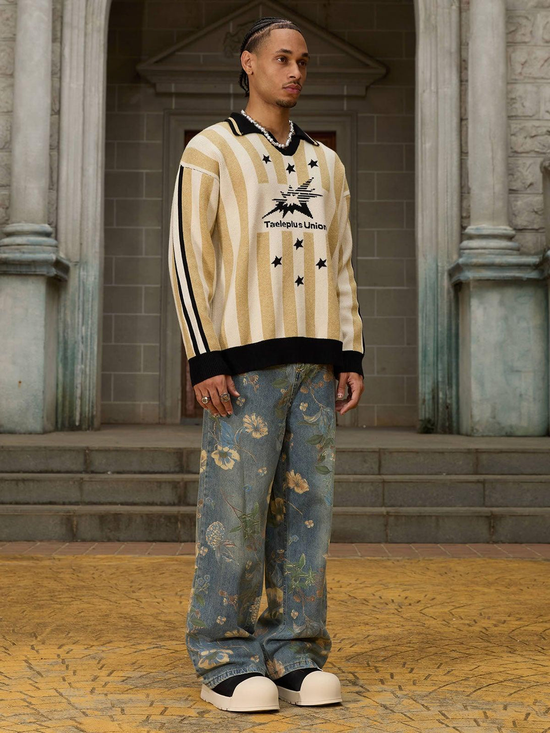 Model in TALISHKO floral carpenter pants and striped sweater, highlighting casual elegance.