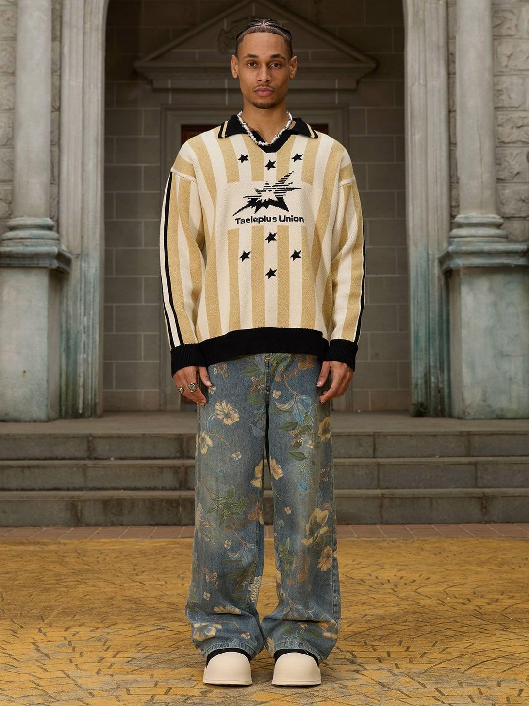 Model wearing relaxed-fit floral carpenter pants by TALISHKO, paired with a striped sweater.