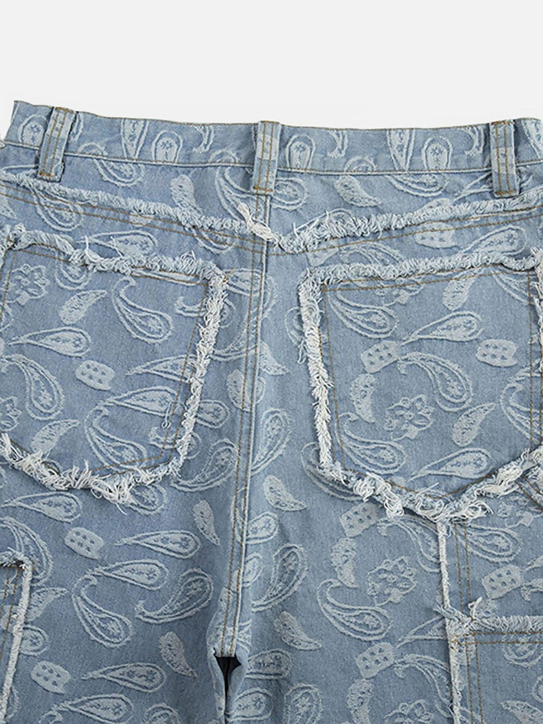 Focusing on the intricate paisley pattern and frayed edges of TALISHKO's cashew flower cut jeans.