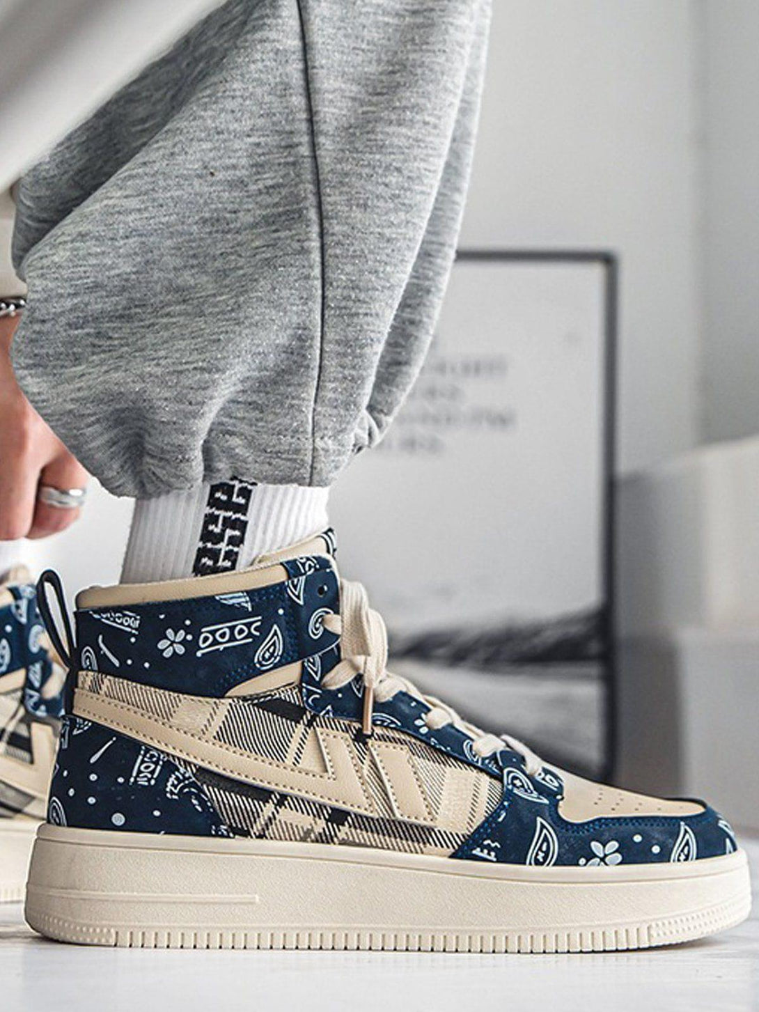 TALISHKO high-top sneaker in beige and blue with paisley pattern, worn with gray joggers.