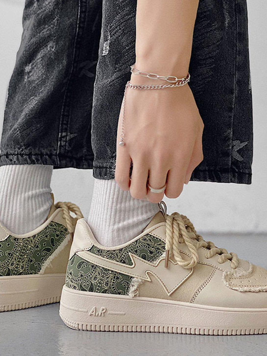 TALISHKO canvas shoes with green paisley patchwork, styled with dark jeans and a silver bracelet.