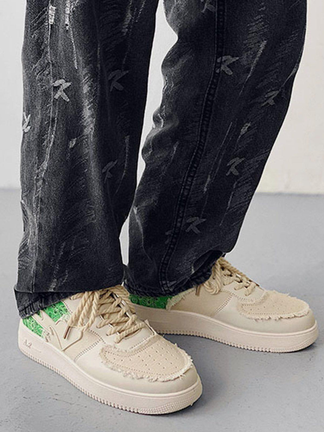 TALISHKO canvas shoes with beige patchwork accents, paired stylishly with dark patterned jeans.