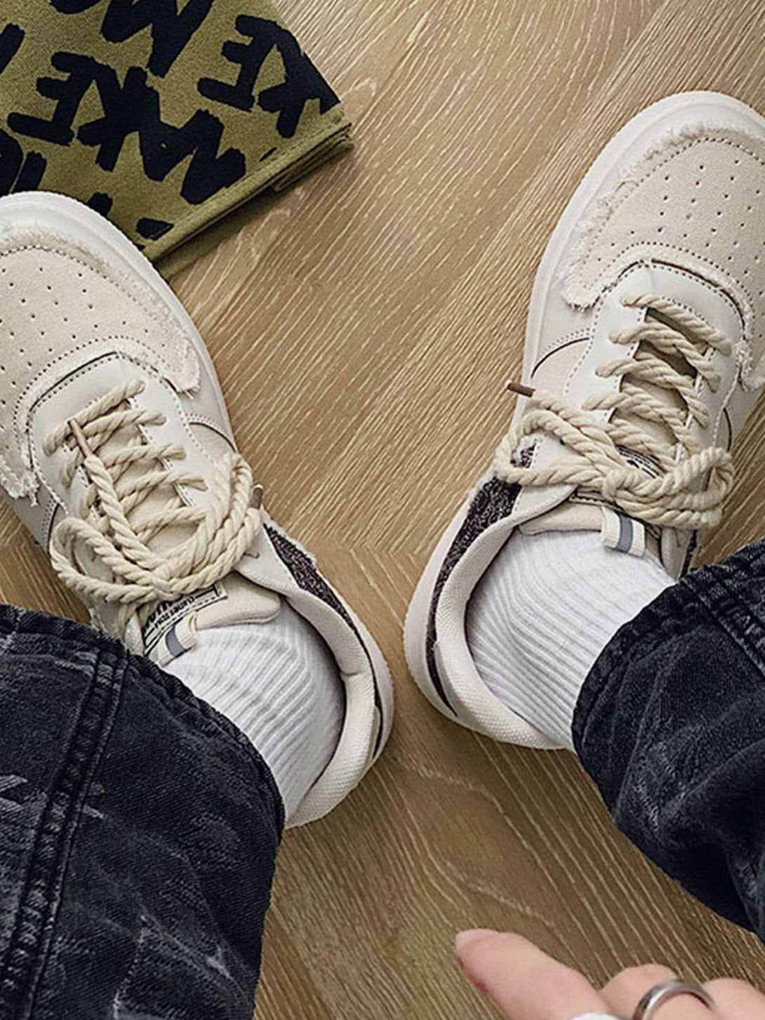 Intricate look at TALISHKO canvas shoes with patchwork detailing, styled with dark jeans.