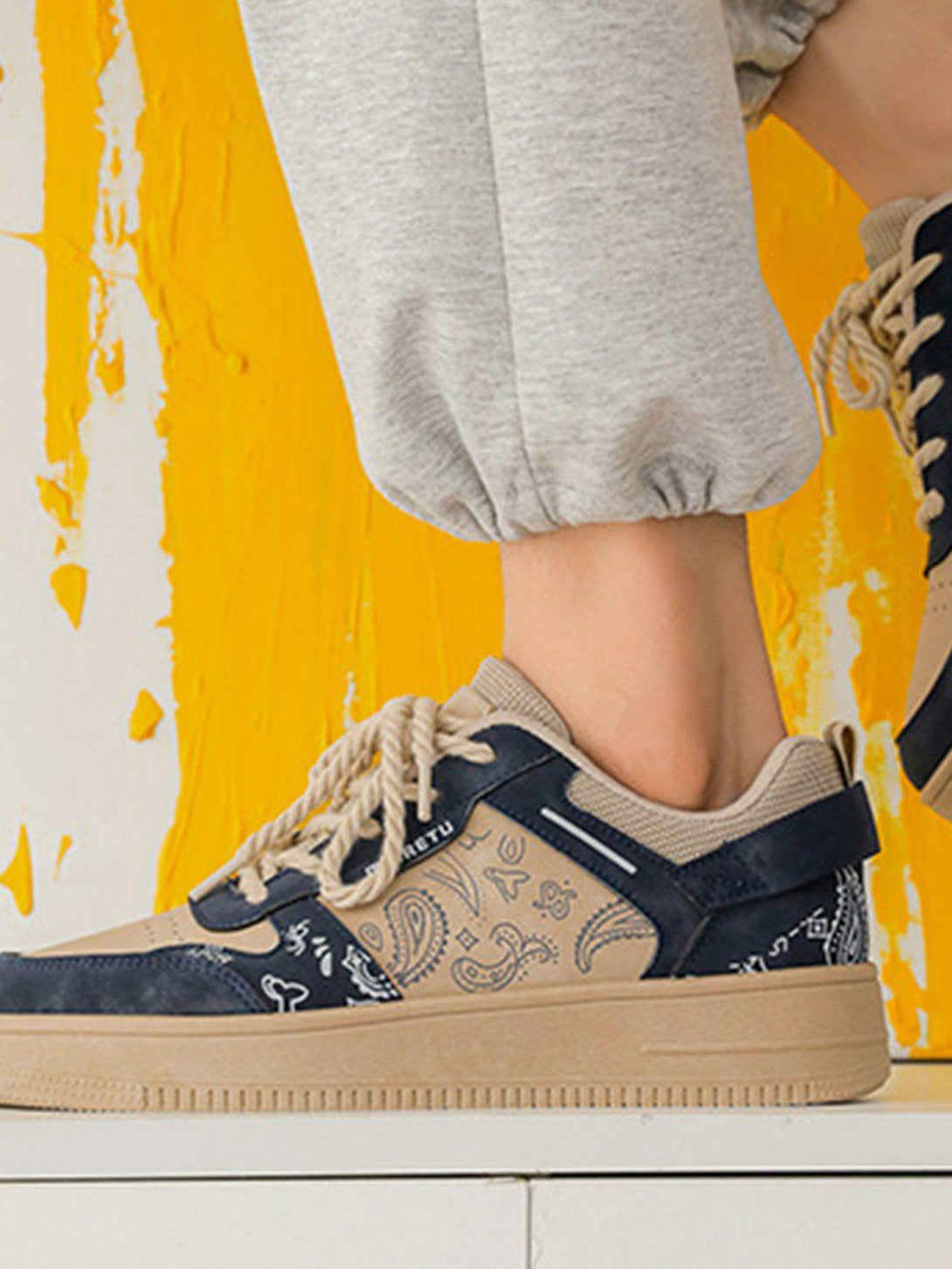 A detailed look at TALISHKO men's shoes featuring a cashew flower print, paired with joggers.