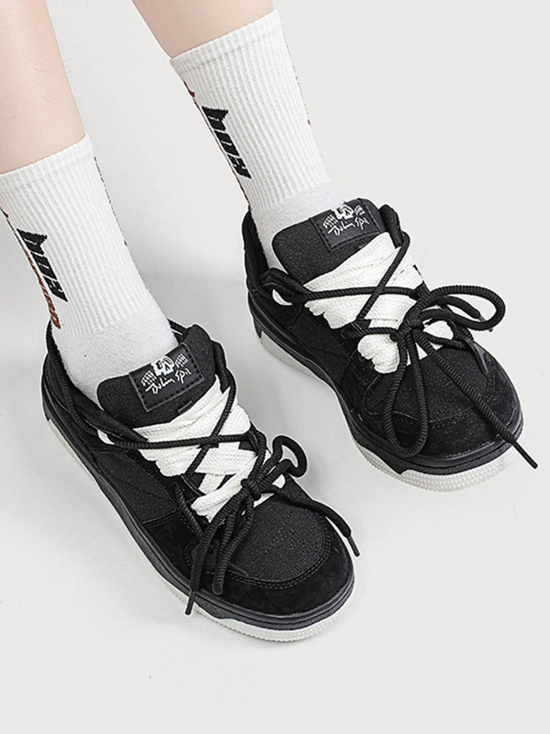 TALISHKO sports shoes in black with white laces, paired with white socks for a trendy look.
