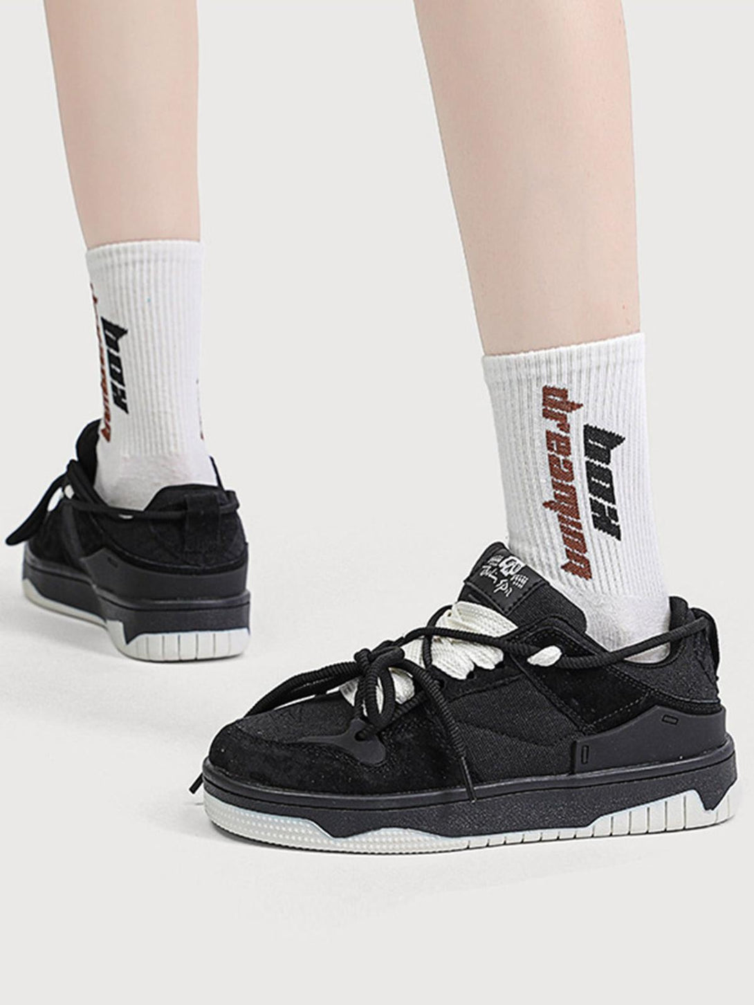 TALISHKO sports shoes in black with bold laces, paired with white socks for a chic street style.