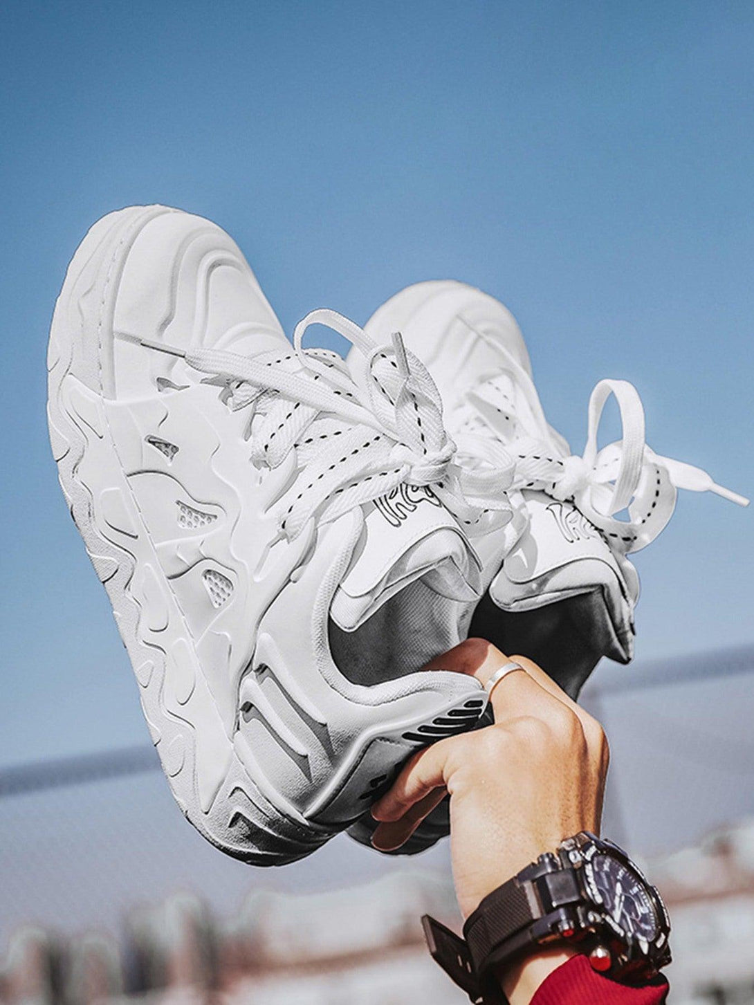 TALISHKO casual plate shoes in white, held up against the sky, showcasing trendy design.