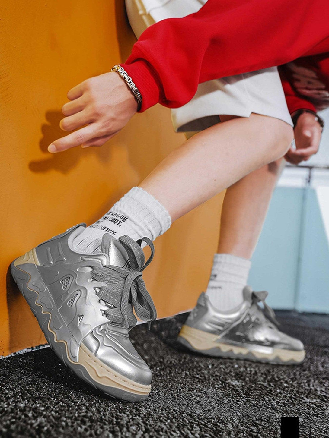 Silver casual plate shoes by TALISHKO, worn with white socks and a red sleeve, showcasing urban style.