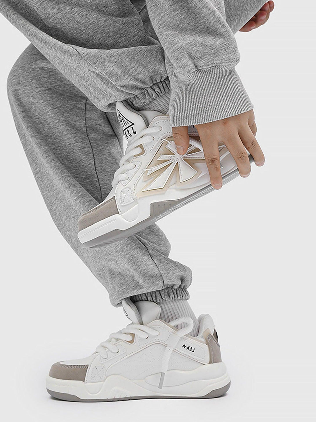 TALISHKO preppy sneakers in white, styled with gray joggers for a casual, sporty vibe.