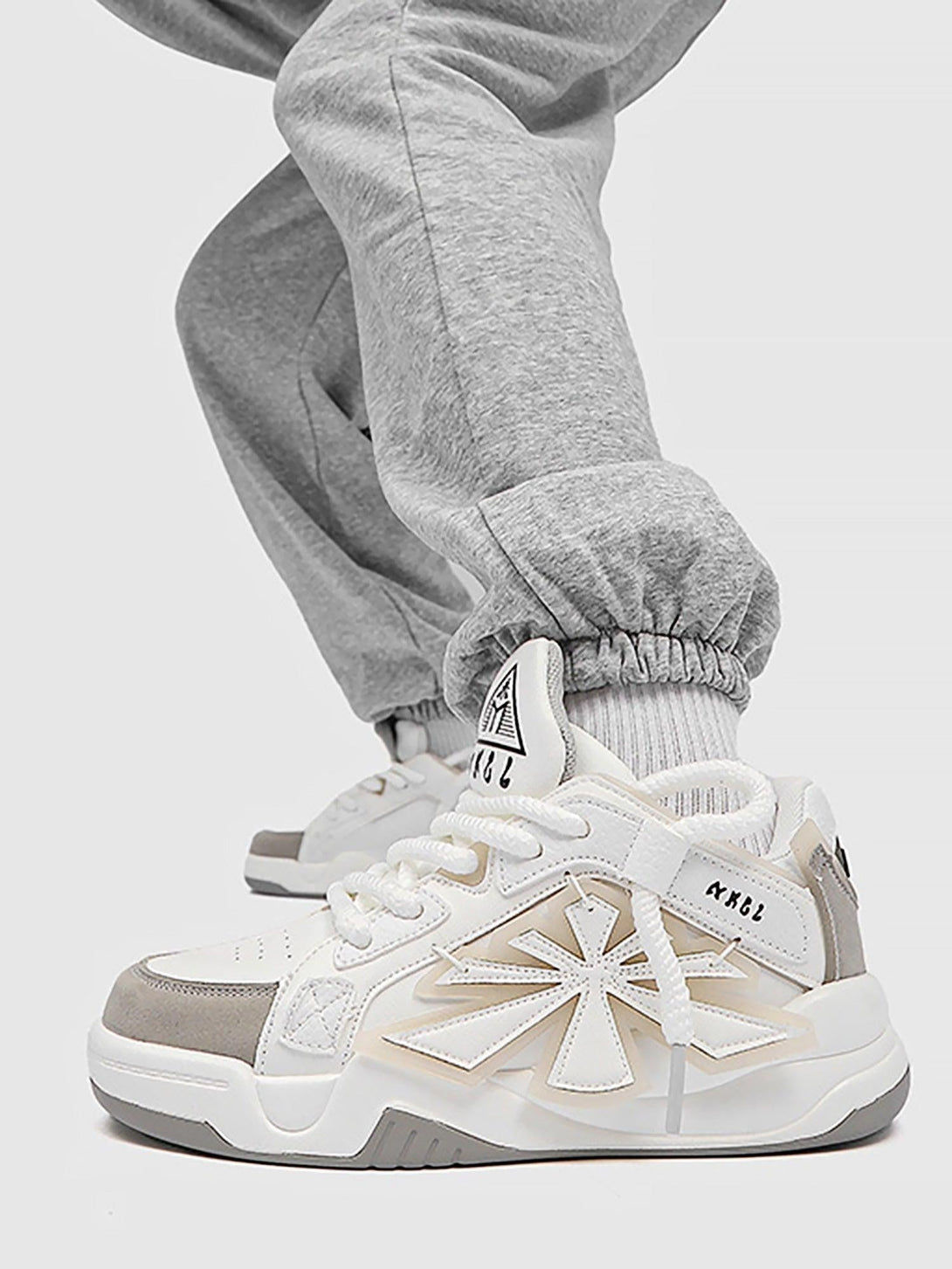 TALISHKO white preppy sneakers paired with gray joggers, highlighting a trendy street style.