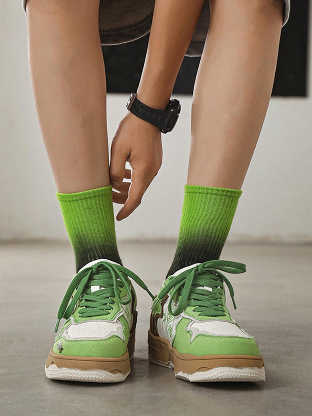 TALISHKO's green board shoes with thick soles, worn with gradient socks, front view.