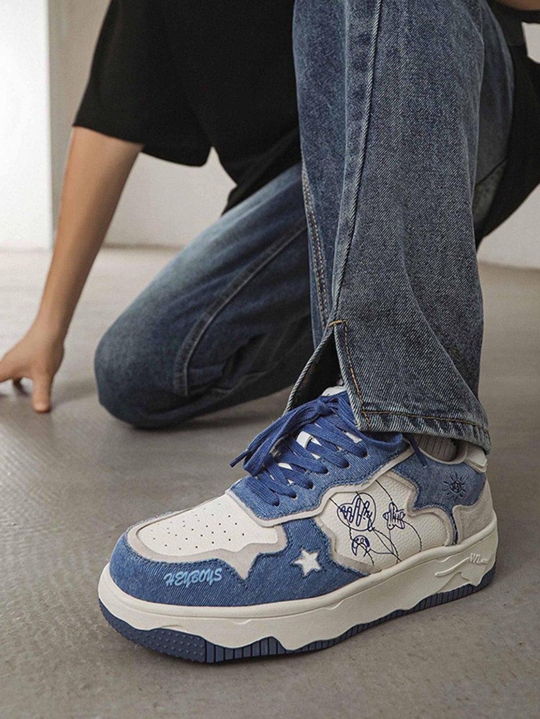 TALISHKO's casual sneakers in blue with star details, worn with denim for a trendy look.