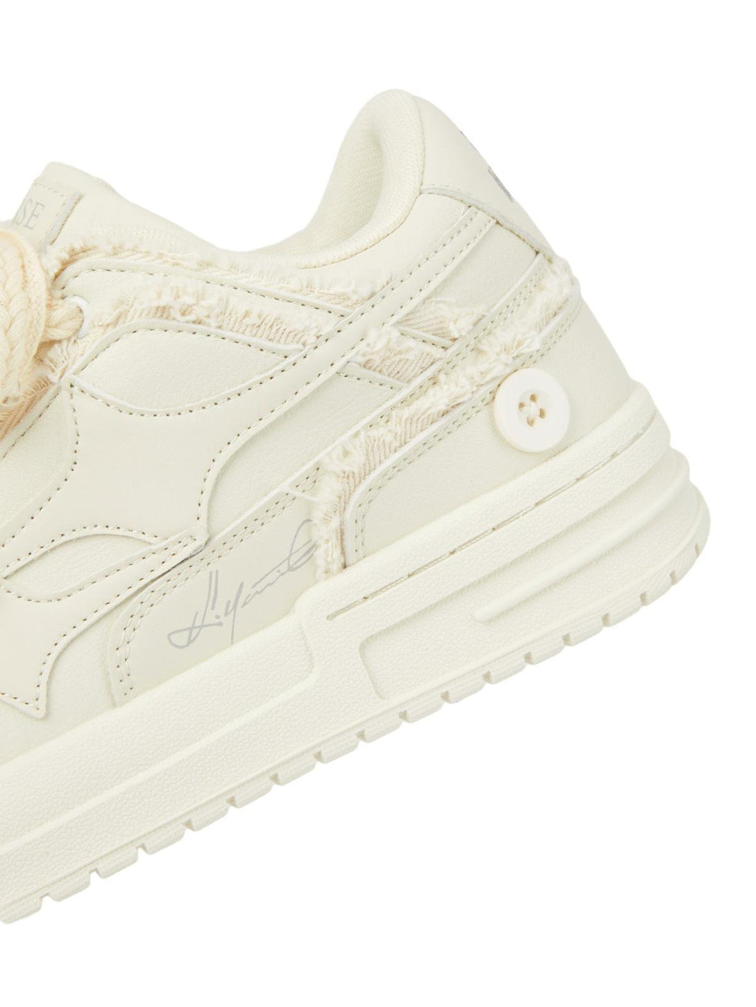 Intricate look at TALISHKO's casual white board shoe detailing, showcasing unique textured accents.