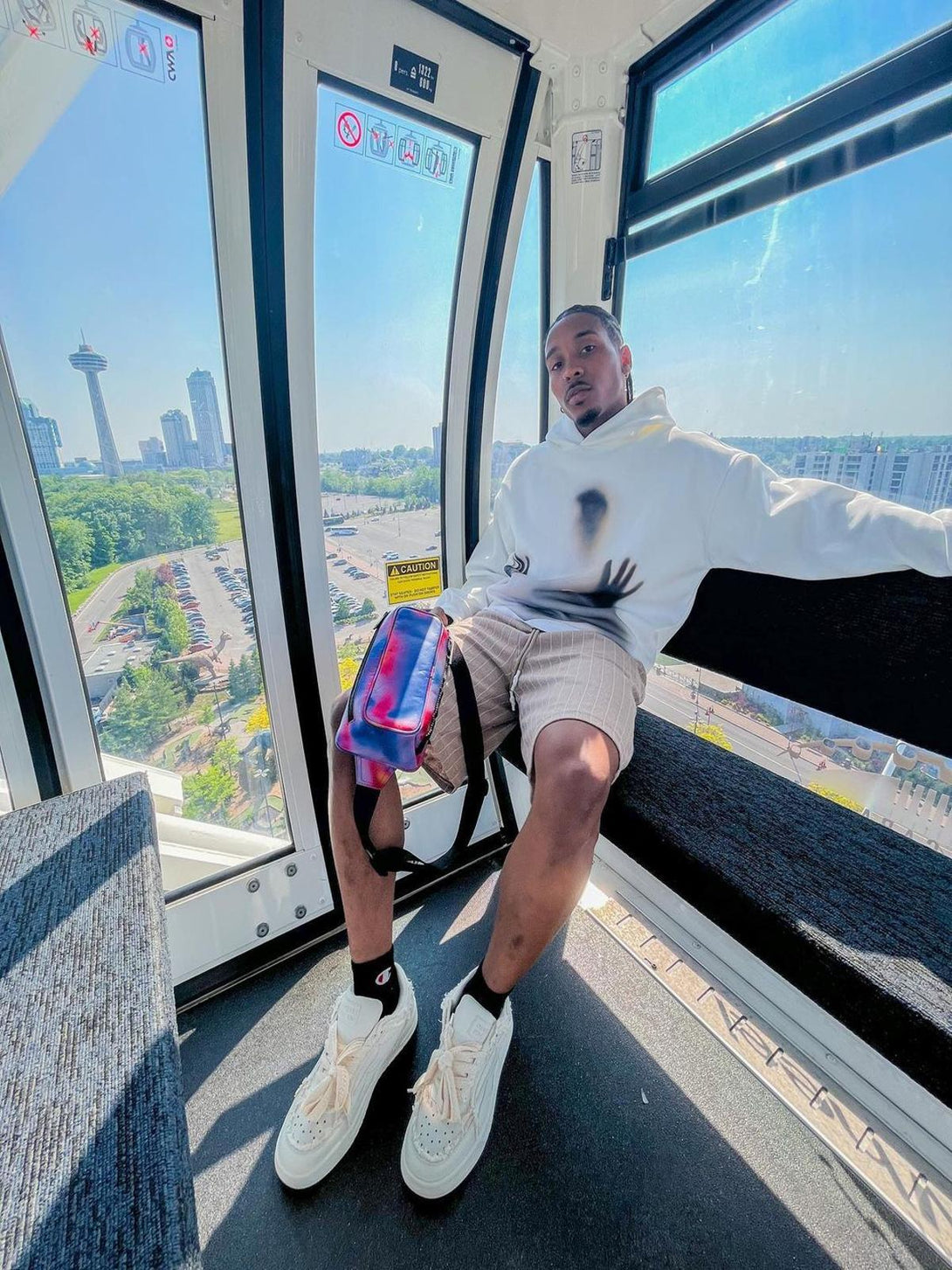 A person in a ferris wheel cabin wearing TALISHKO casual white board shoes and a stylish outfit.