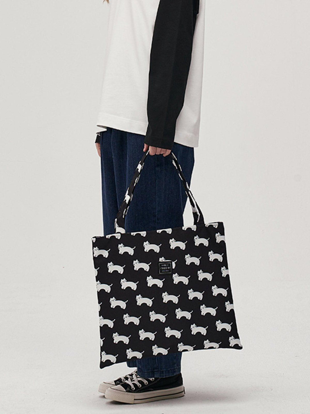 TALISHKO canvas shoulder bag with playful white cat pattern, modeled with casual attire.