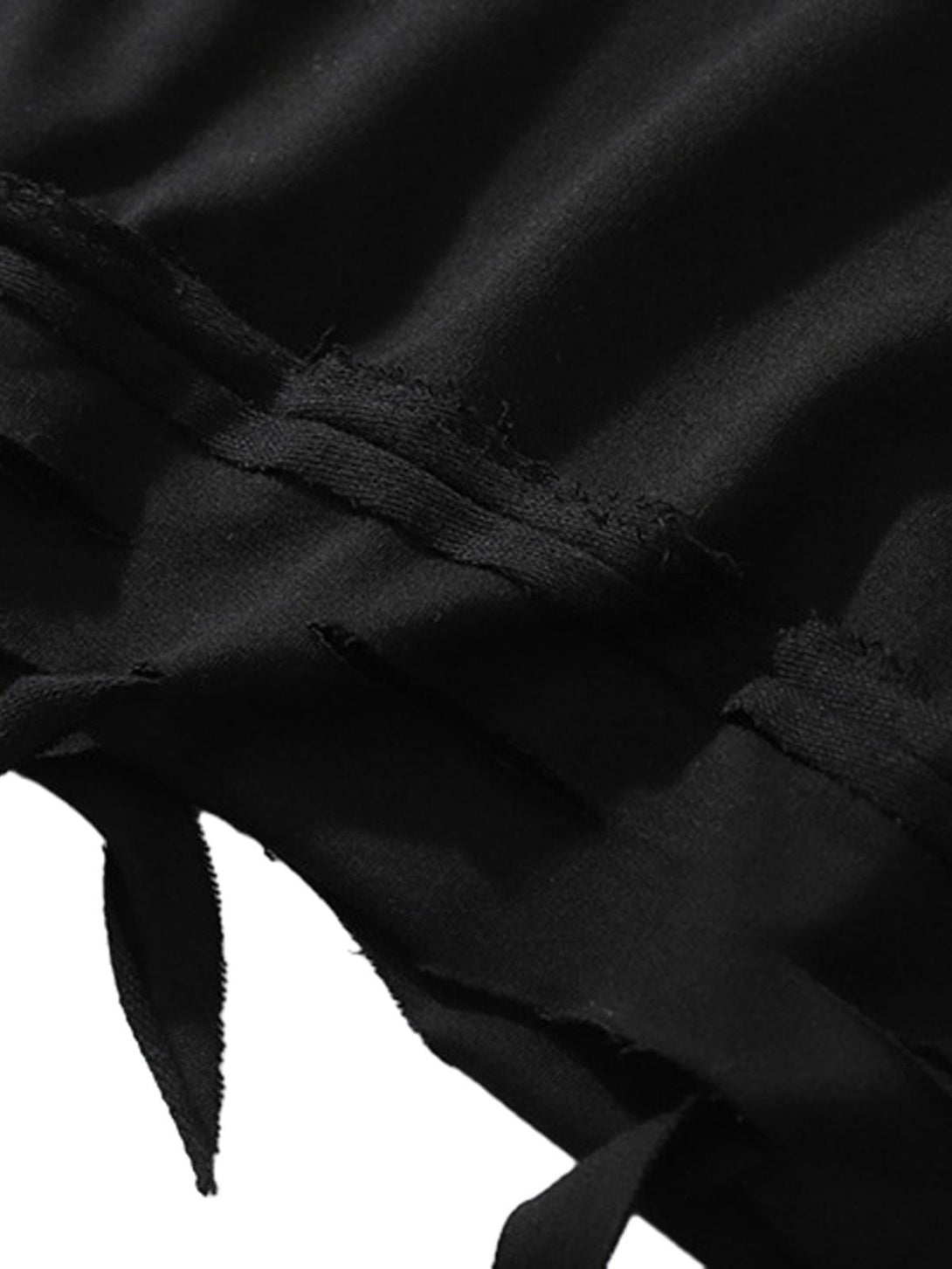 A detailed view of the distressed hem on a black oversized T-shirt by TALISHKO.