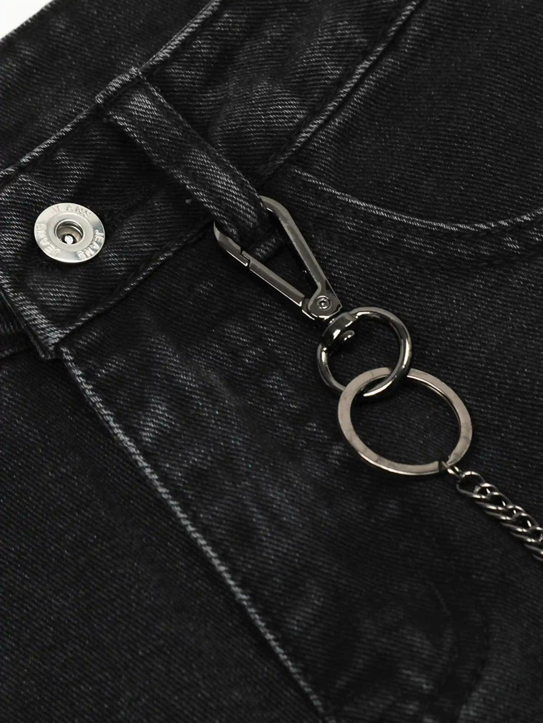 A detailed view of TALISHKO black cargo jeans featuring chain accents and sturdy stitching.