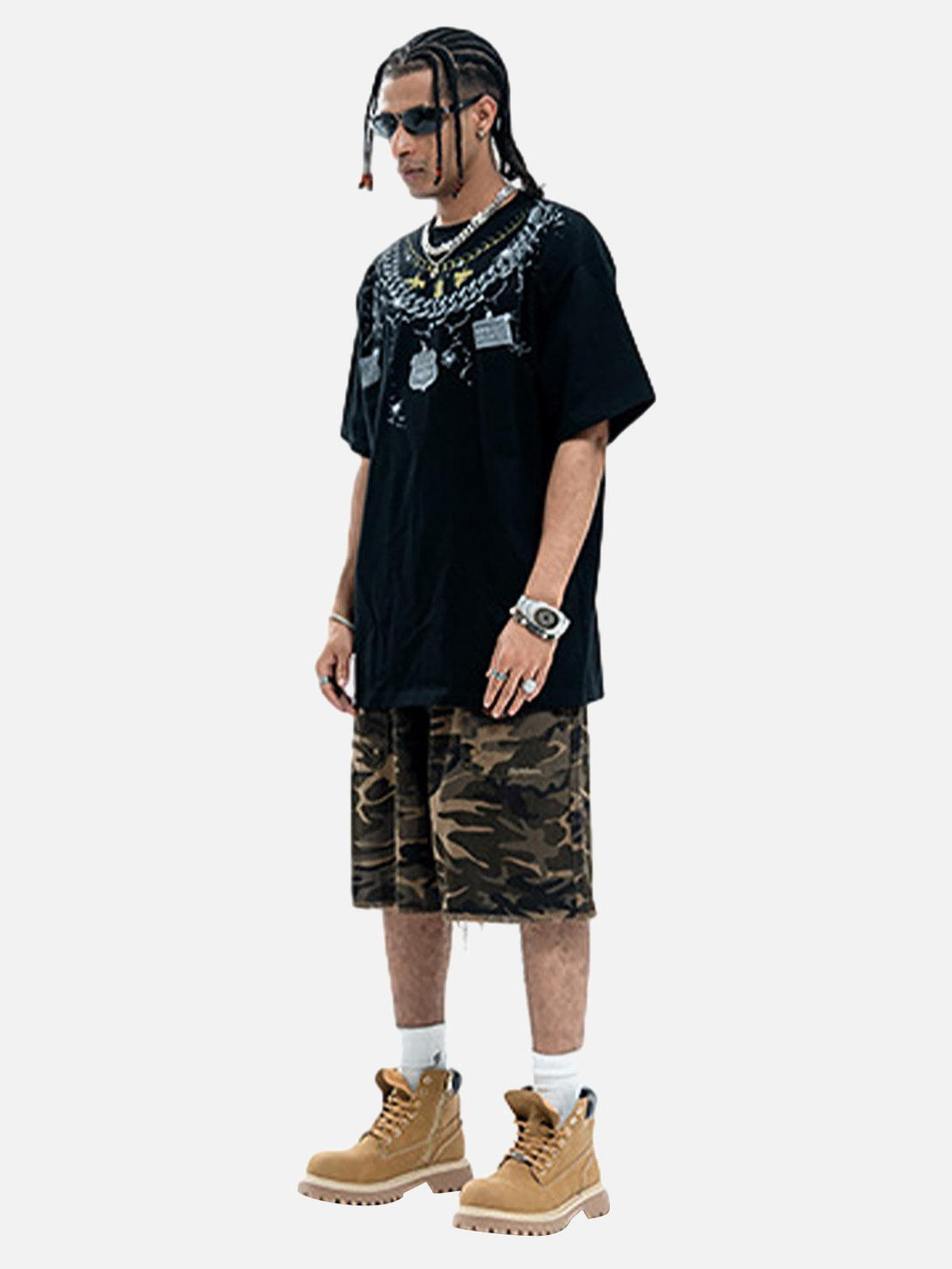 Model wearing TALISHKO chain print T-shirt with camo shorts and boots, offering a relaxed vibe.
