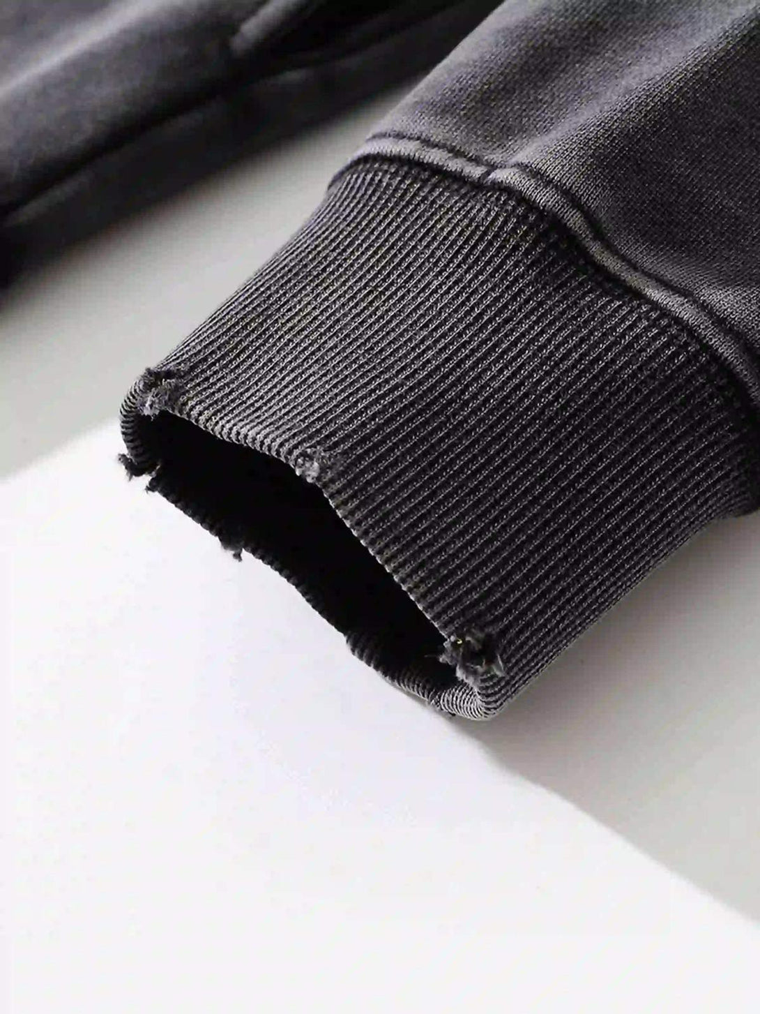 A detailed view of the worn cuff on a TALISHKO hip-hop style hoodie, highlighting its rugged texture.