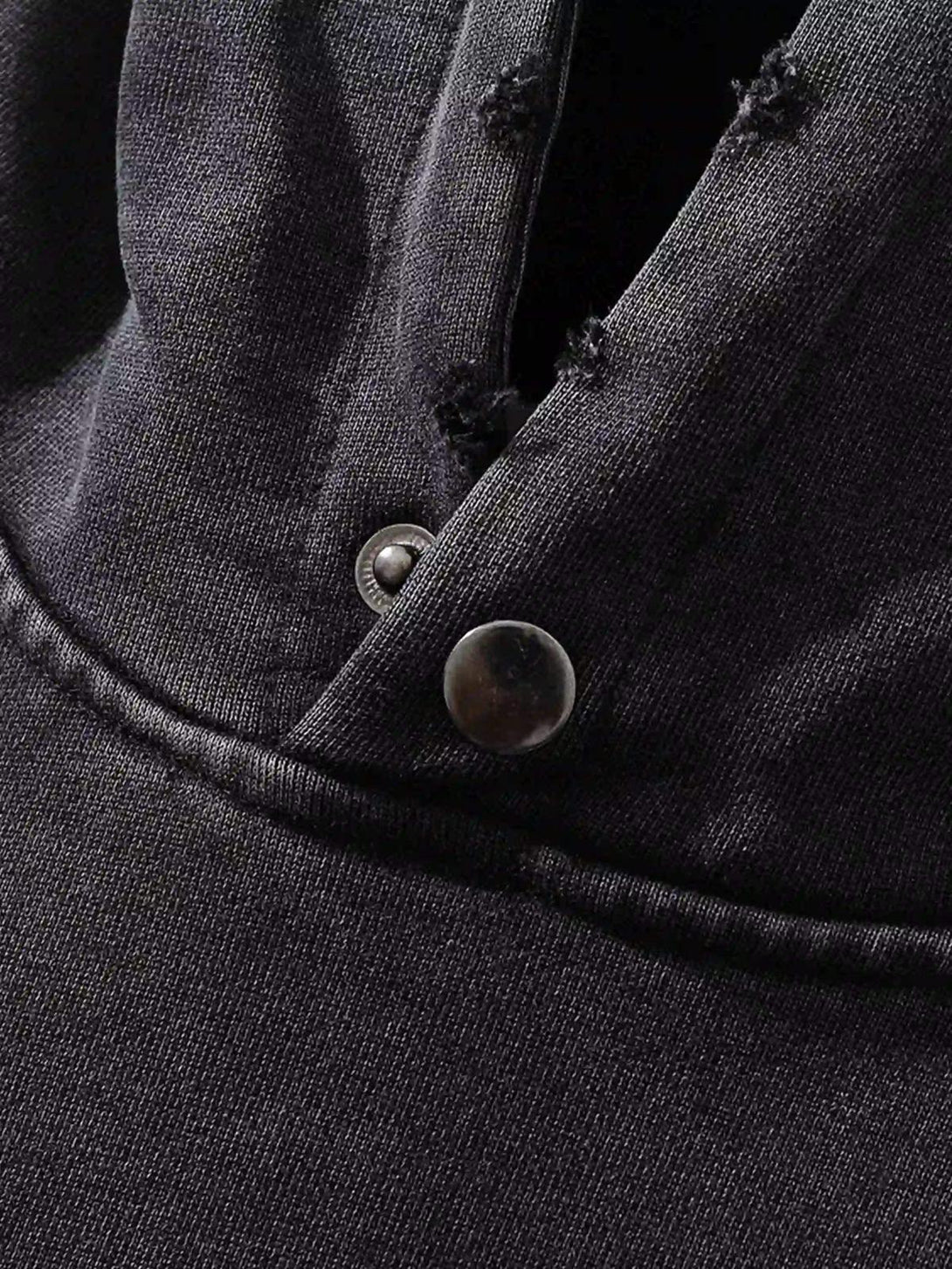 Close-up of distressed black fabric and stitching on a loose hoodie by TALISHKO, highlighting texture.