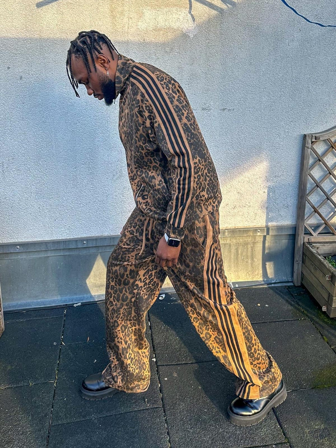 Model in a cheetah print suede track jacket and pants by TALISHKO, side view with bold stripes.