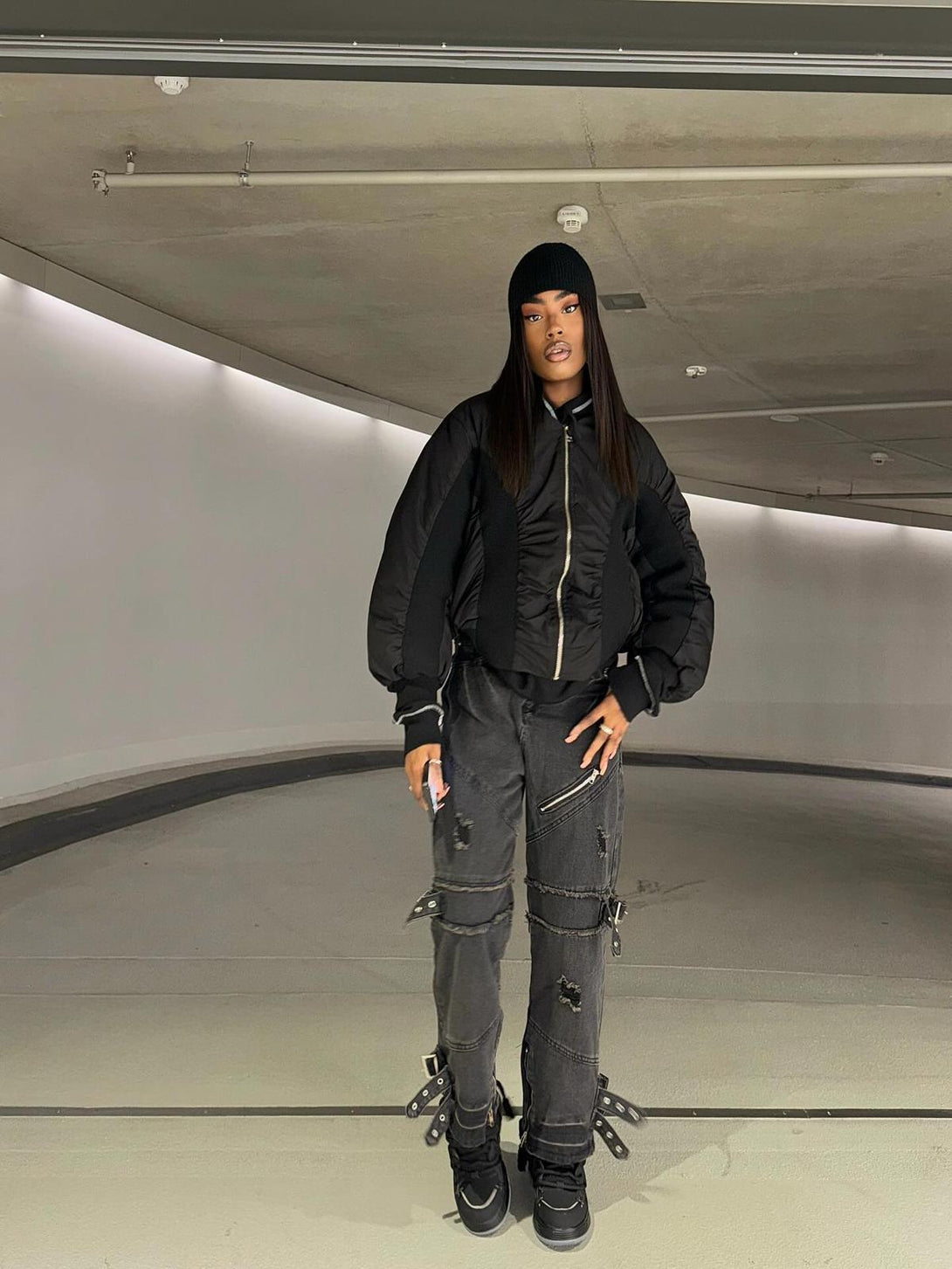 Model wearing black streetwear ensemble with chunky rope shoes by TALISHKO in urban setting.