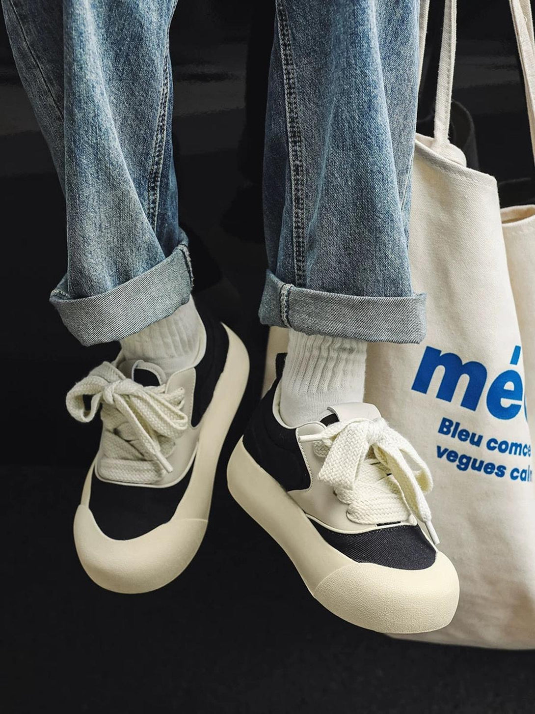 Casual style with TALISHKO's chunky color-block sneakers in black and cream, paired with jeans.