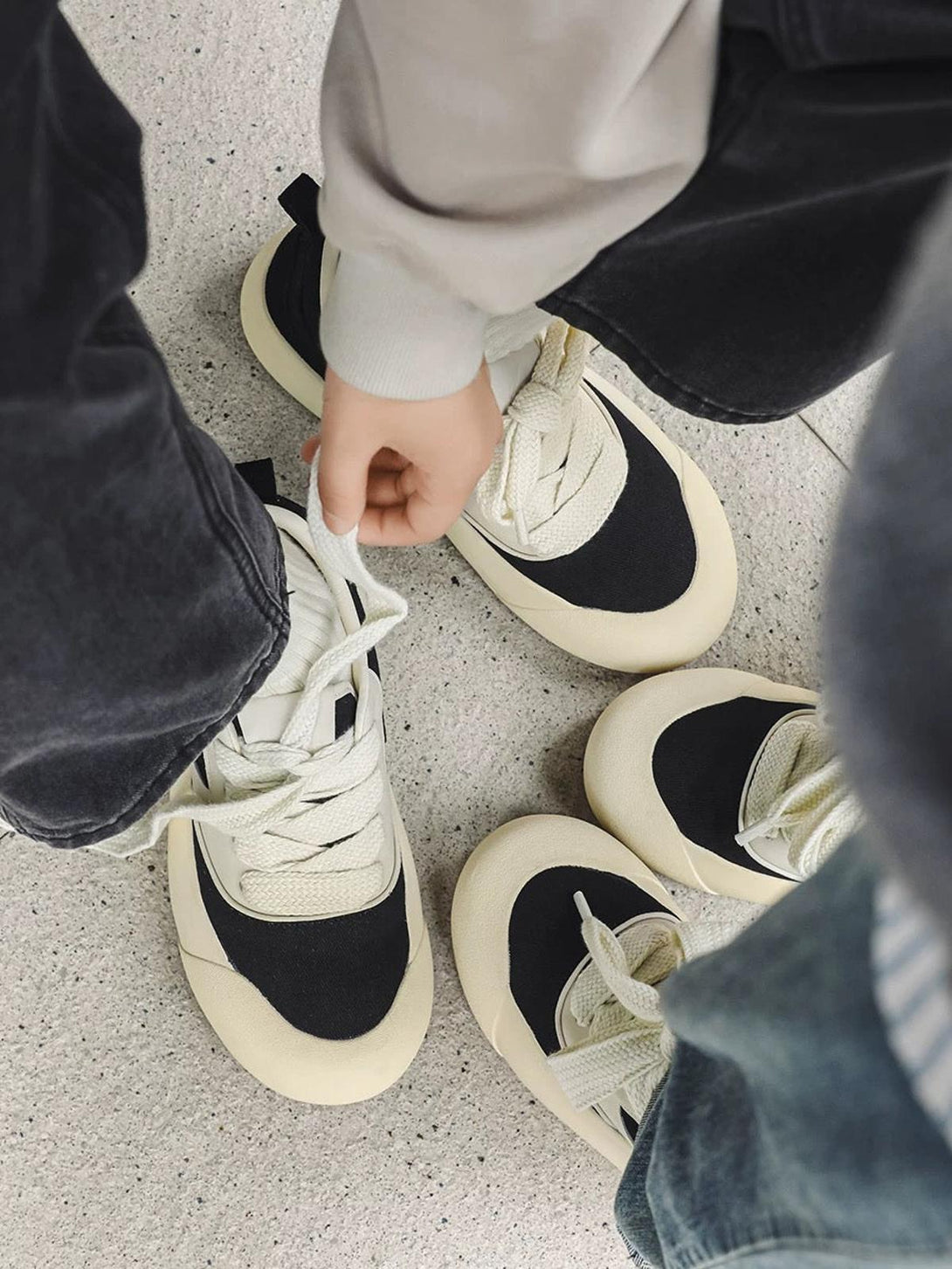 Two people sporting TALISHKO's chunky color-block sneakers in a trendy black and cream style.
