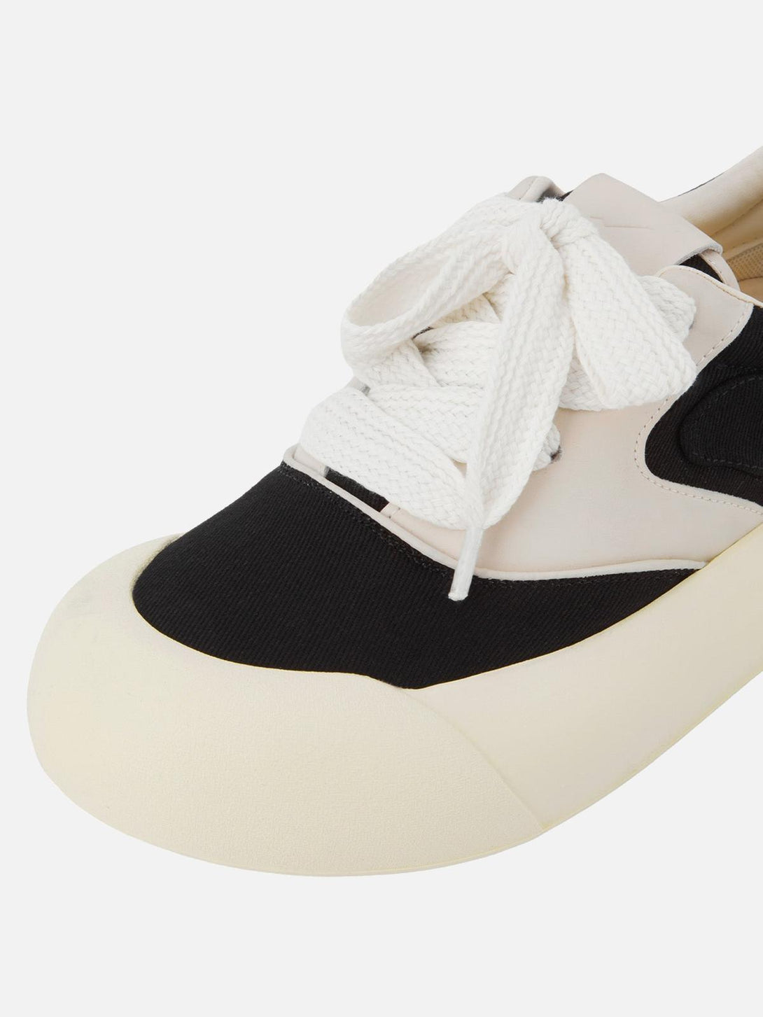 A close-up of TALISHKO's chunky sneakers highlighting the unique black and cream color-block design.