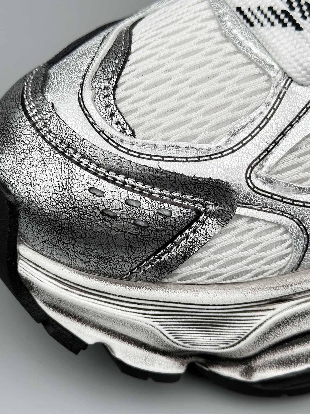 Zoomed-in texture of TALISHKO chunky sole running sneakers, highlighting intricate metallic details.