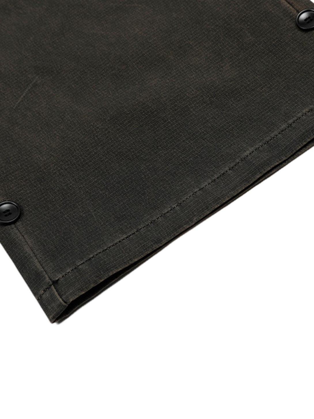 A detailed view of TALISHKO's classic cargo pants fabric and button detail in a dark shade.