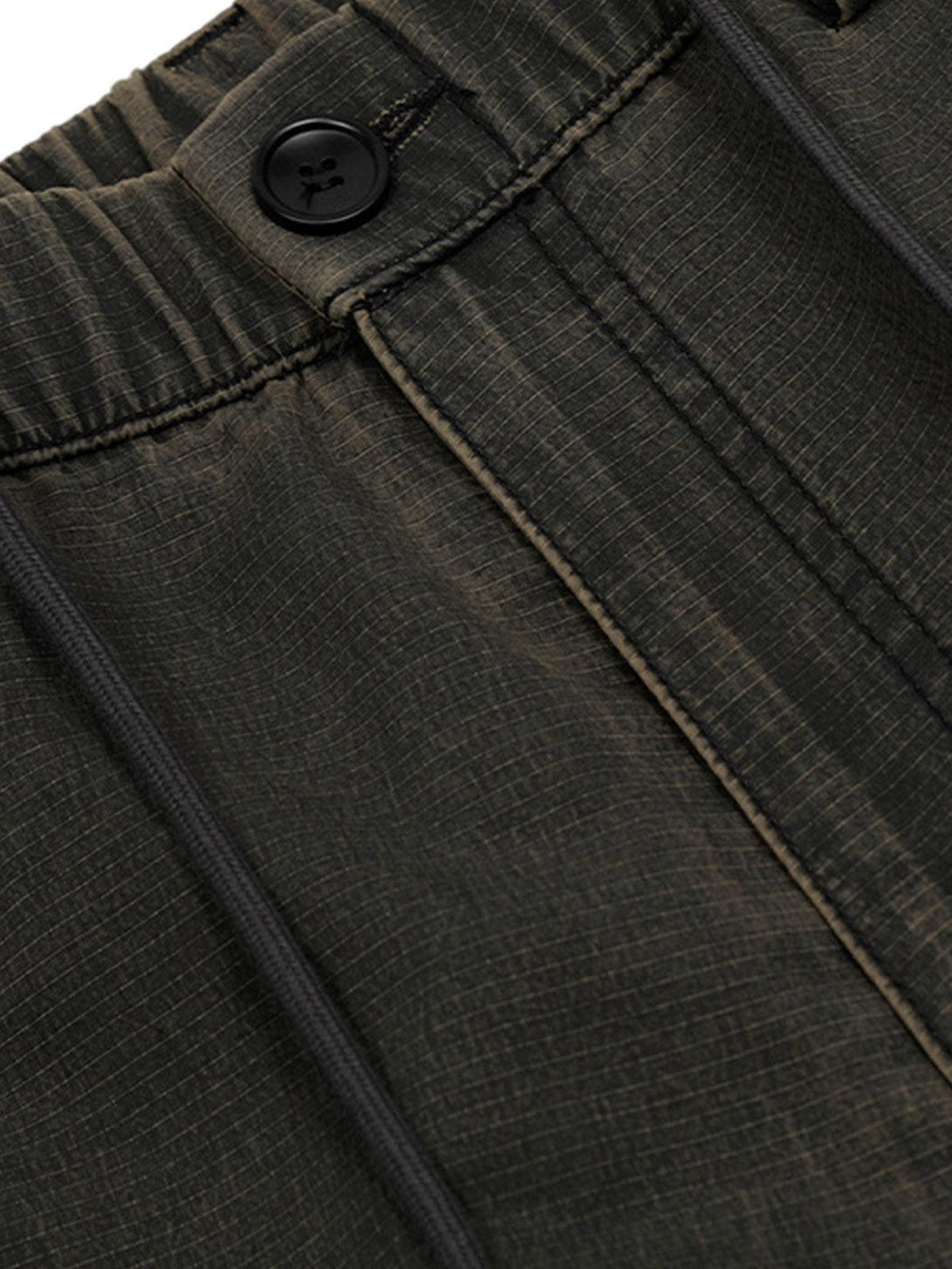 Focusing on the texture and stitching of TALISHKO's classic cargo pants in a dark shade.