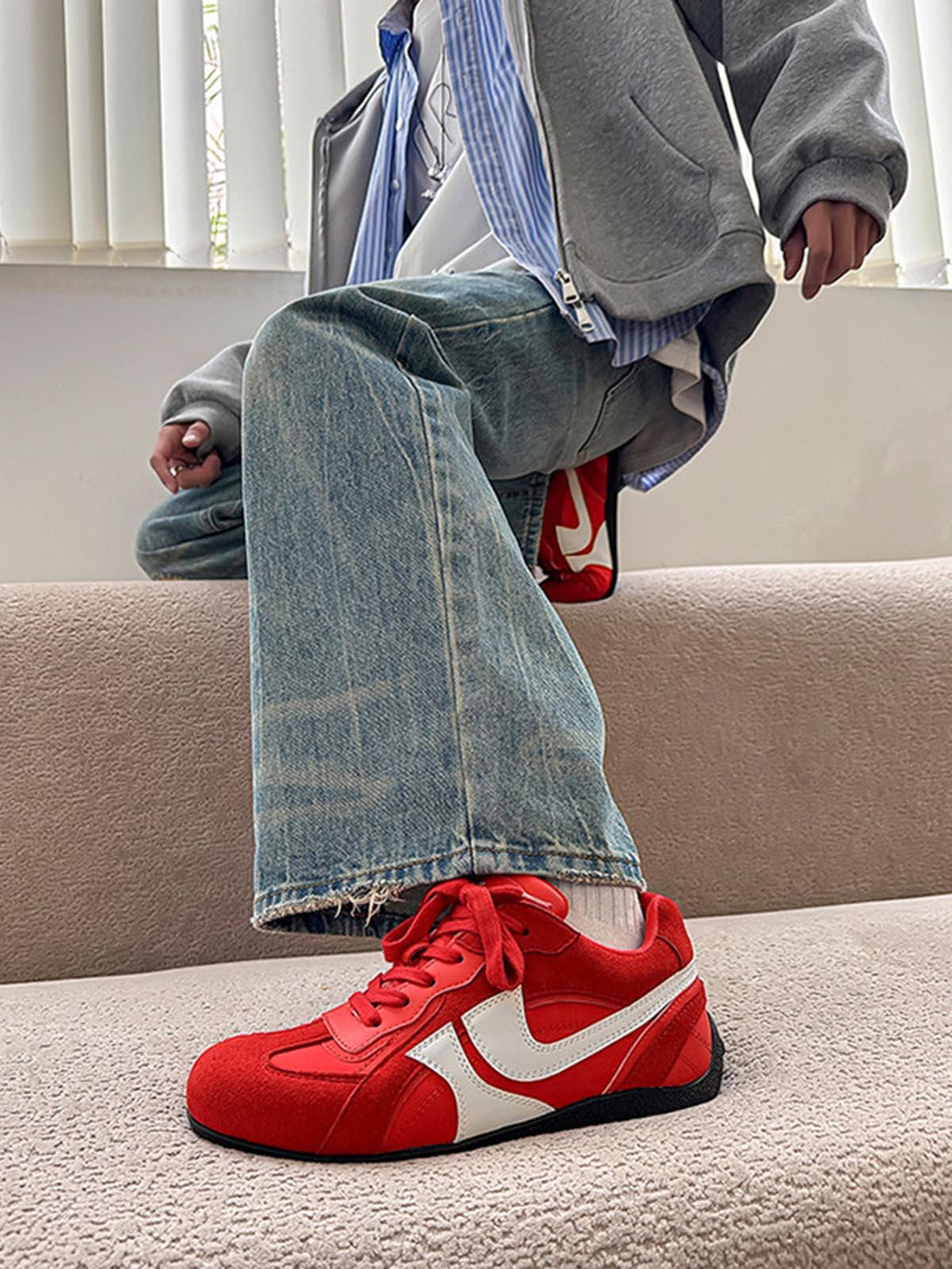 TALISHKO red suede low-top sneakers with white accents, paired with casual denim jeans.