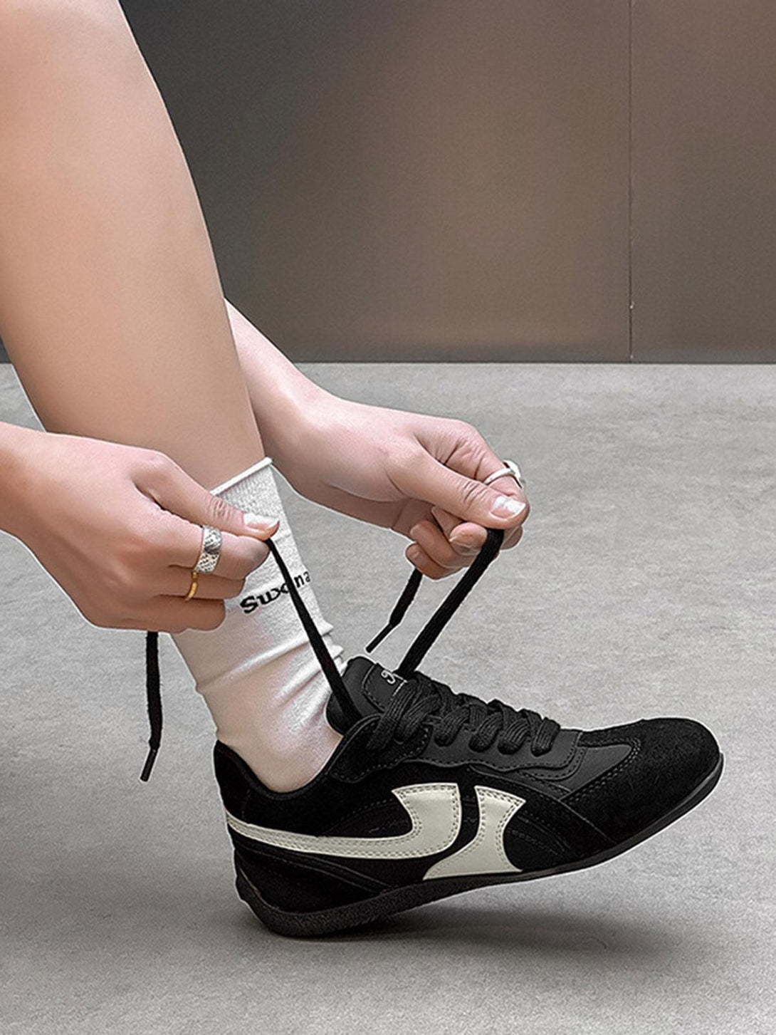 TALISHKO black suede low-top sneakers with white details, laced up for a sleek finish.