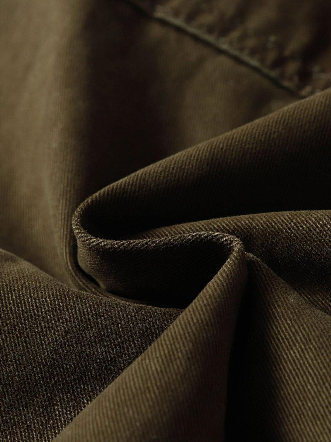 Zoomed-in texture of TALISHKO's cargo pants, highlighting the rich brown fabric and weave.